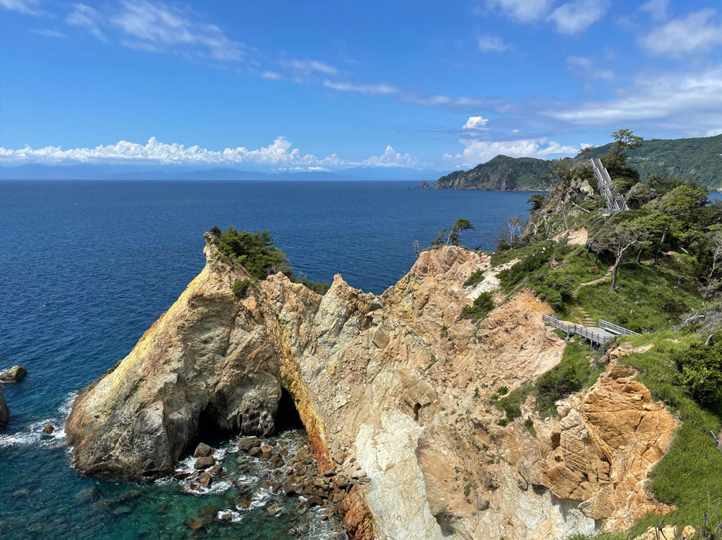 青い空と海を背景に、岩肌と緑が織りなす絶景の岬が広がっています