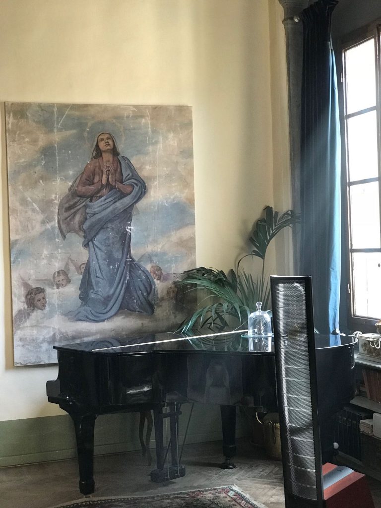 祈る人物の宗教画とピアノがある部屋